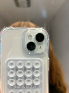 a close up of a person holding a cell phone in front of their face with circles on it