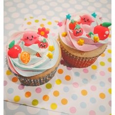 two decorated cupcakes sitting on top of a table