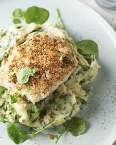 a white plate topped with pasta and spinach covered in seasoning sprinkles