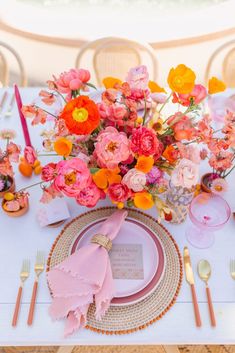 the table is set with pink and orange flowers