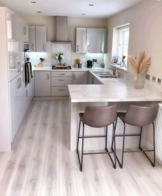 a kitchen with two stools at the counter and an island in front of it