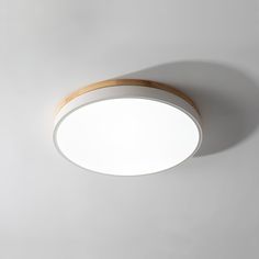 a white ceiling light with wooden trim and dimmer on the top, against a gray wall