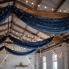 the ceiling is decorated with lights and blue draping for an elegant wedding reception