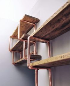 three wooden shelves with metal piping on the wall next to each other in a room