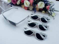 four pairs of sunglasses sitting on top of a white table next to flowers and a bouquet