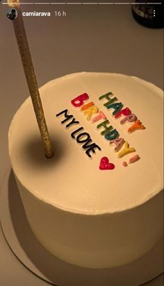 a white cake with the words happy birthday written on it and a matchstick sticking out of it