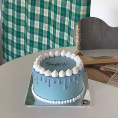 a blue cake sitting on top of a table next to a green and white checkered curtain