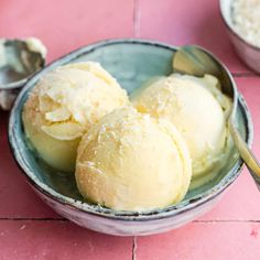 three scoops of ice cream sit in a bowl on a pink tile floor next to spoons