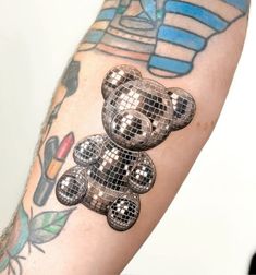 a person with a tattoo on their arm has a teddy bear made out of disco balls