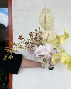 a person's hand holding a bouquet of flowers on the outside of a building