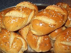 a pile of bread rolls sitting on top of a metal pan covered in sesame seeds