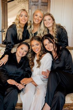 a group of women sitting on top of a bed in matching black and white pajamas