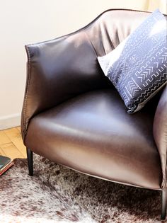 a brown leather chair sitting on top of a wooden floor next to a phone charger