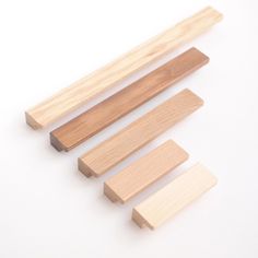 three pieces of wood sitting next to each other on a white surface with one piece missing