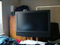 a flat screen tv sitting on top of a wooden stand in front of a window