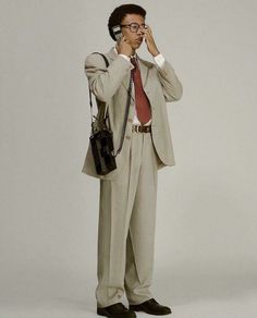 a man in a suit and tie talking on a cell phone while holding a handbag