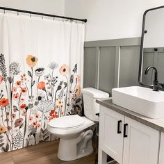 a white toilet sitting next to a sink under a bathroom mirror with a shower curtain