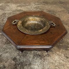 an old wooden box with a metal bowl on it's lid sitting on the floor