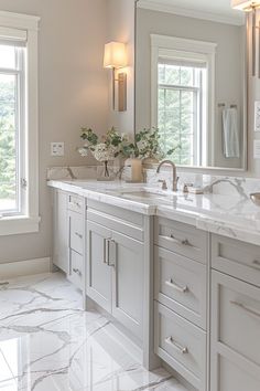 a large bathroom with two sinks and marble counter tops in front of three windows on either side of the sink