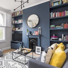 a living room with bookshelves, couches and a mirror on the wall