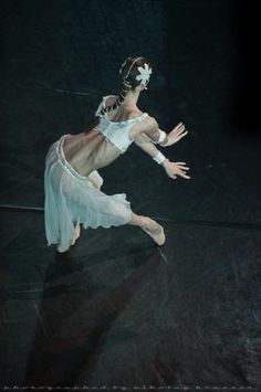 a ballerina in white is performing on the floor with her arms outstretched and legs spread out