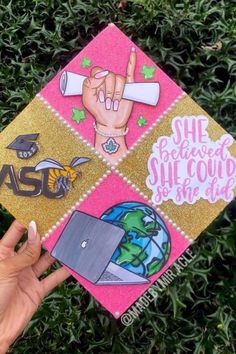 someone holding up a pink and gold graduation cap with different stickers on the top