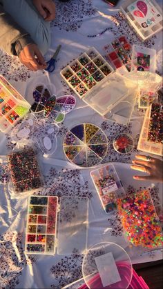 the table is covered with lots of beads and other crafting supplies for kids to make