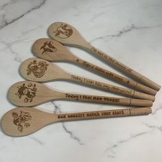 six wooden spoons with different designs on them sitting on a marble counter top,