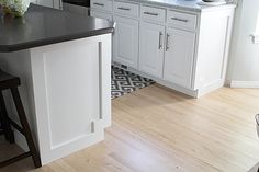 a kitchen with white cabinets, black counter tops and an island in front of the stove