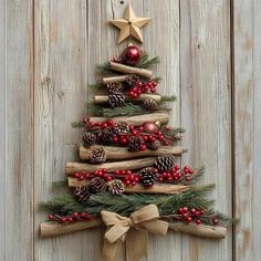 a wooden christmas tree with red berries and pine cones on the top is hanging on a wall