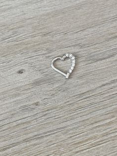 a heart shaped ring sitting on top of a wooden table