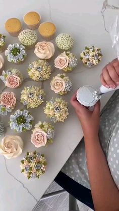 a woman is decorating cupcakes with flowers