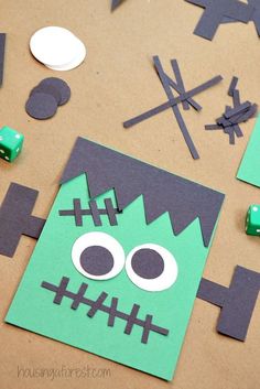 paper cut out to look like a monster with green eyes and black nose, surrounded by other crafting supplies