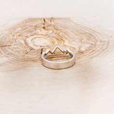 a silver ring sitting on top of a piece of wood