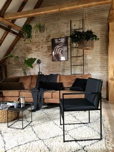 a living room with exposed brick walls and black leather furniture in the corner, along with potted plants