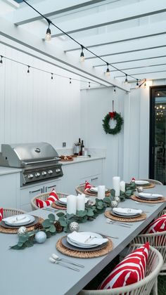 an outdoor kitchen decorated for christmas with red and white striped napkins on the table