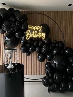 black balloons are on display in front of a happy birthday sign and balloon arch with the words happy birthday