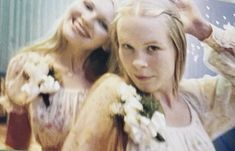 two women standing next to each other with flowers in their hair