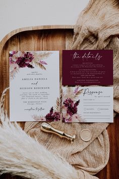 the wedding stationery is laid out on a wooden tray