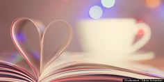 an open book with a heart - shaped page and coffee cup in the background on a table