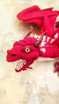 a red knitted dragon laying on top of a table