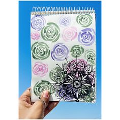 a hand holding up a spiral notebook with flowers on it