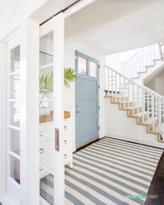 a blue door is open in a white room with black and white stripes on the floor