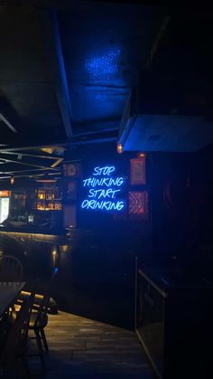 a dimly lit bar with neon signs on the walls and tables in front of it