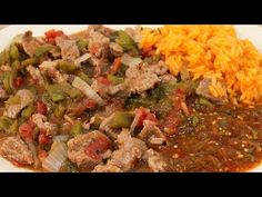 a white plate topped with meat and vegetables next to rice on top of a table