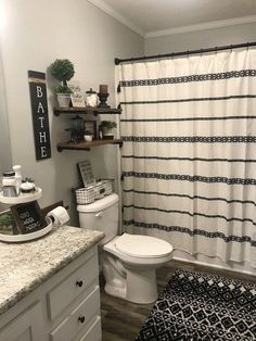 a white toilet sitting in a bathroom next to a bathtub and shower curtain with black trim