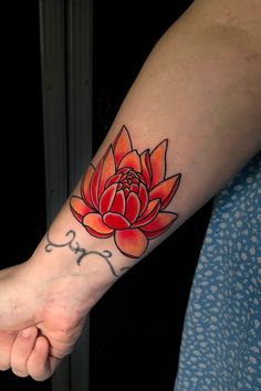 a woman's arm with a red flower tattoo on the left side of her wrist