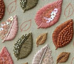 several different types of embroidered flowers and leaves on a piece of fabric with pink thread