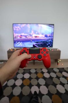 a person holding a red controller in front of a tv