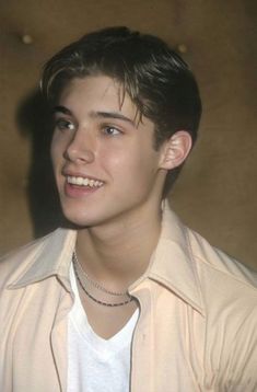 a young man wearing a white shirt and smiling